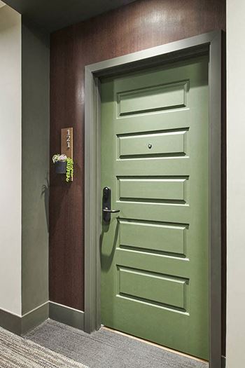 A green door with a handle and a sign on the wall.