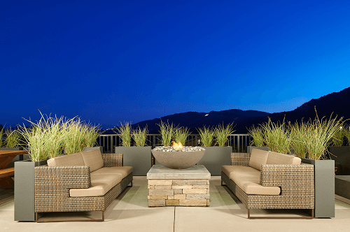 a patio with rattan furniture and a fire pit