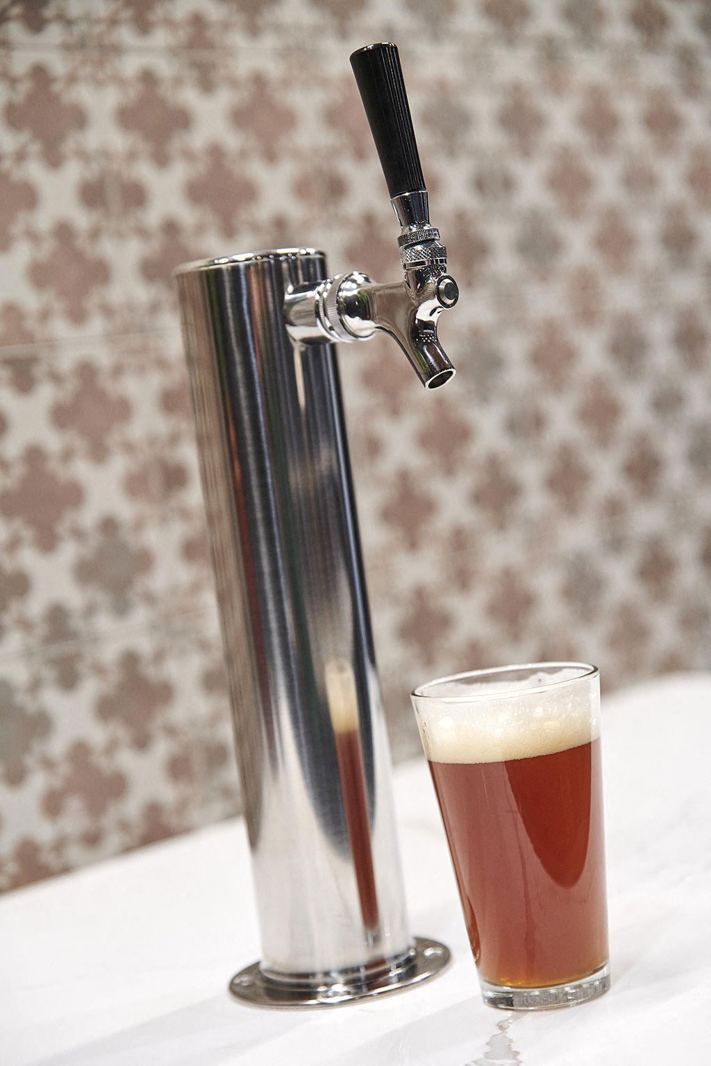 a glass of beer next to a tap