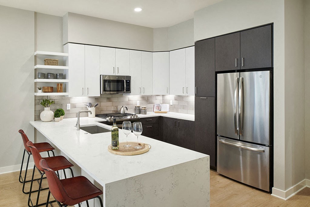 a kitchen with a large island and a stainless steel refrigerator
