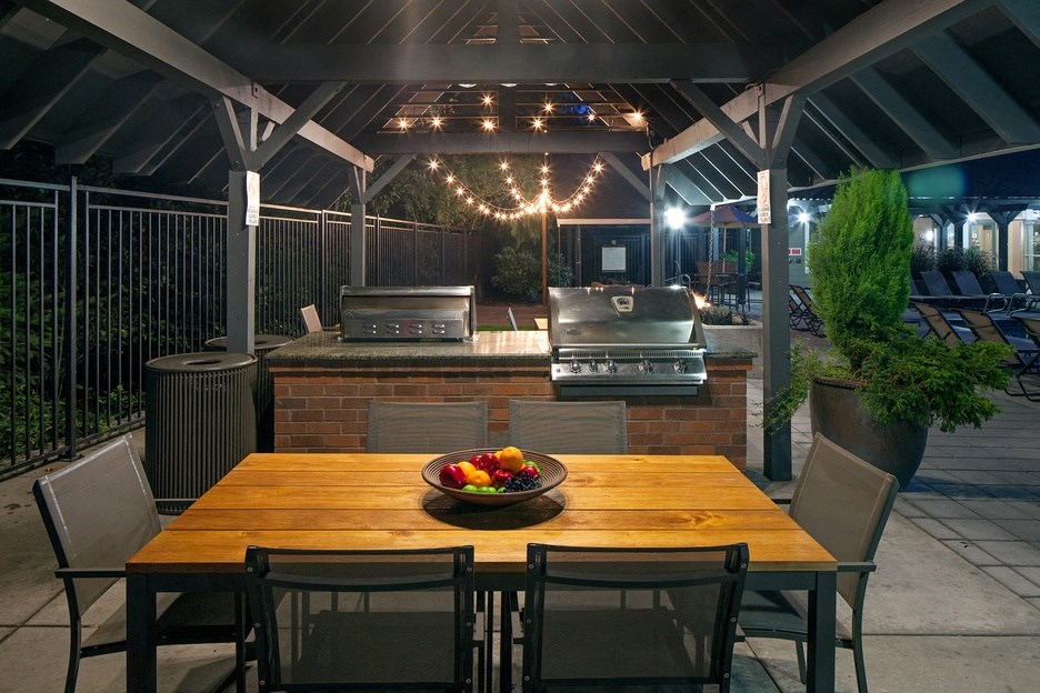 a patio with a dining table and a barbecue grill