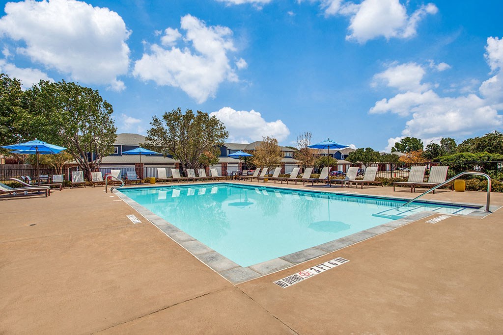 a swimming pool with chaise lounge chairs and umbrellas