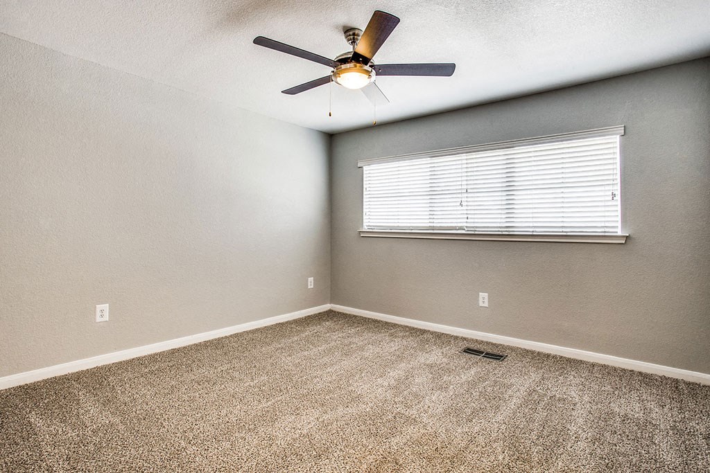 an empty bedroom with a ceiling fan and a window