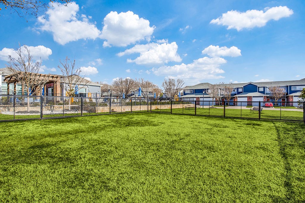 a fenced in grassy area with buildings in the background