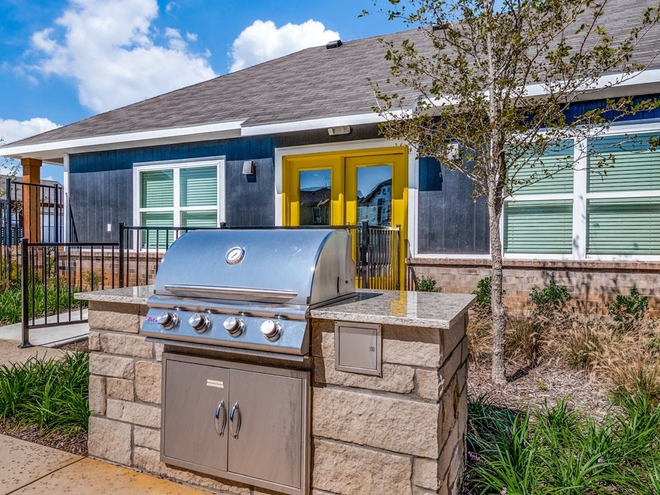 an outdoor kitchen with a grill in front of a house