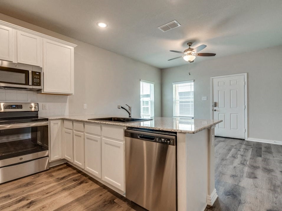 a kitchen with white cabinets and stainless steel appliances