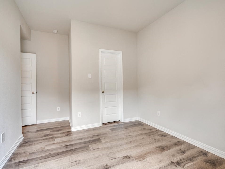 a bedroom with hardwood floors and grey walls