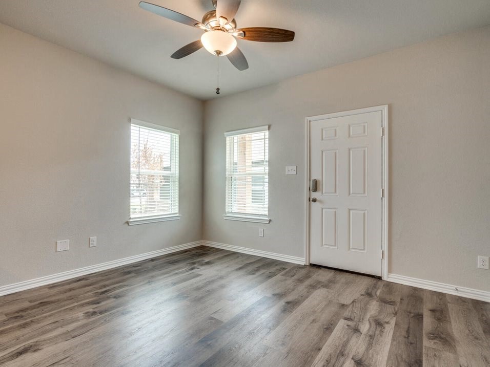 an empty bedroom with a ceiling fan and two windows