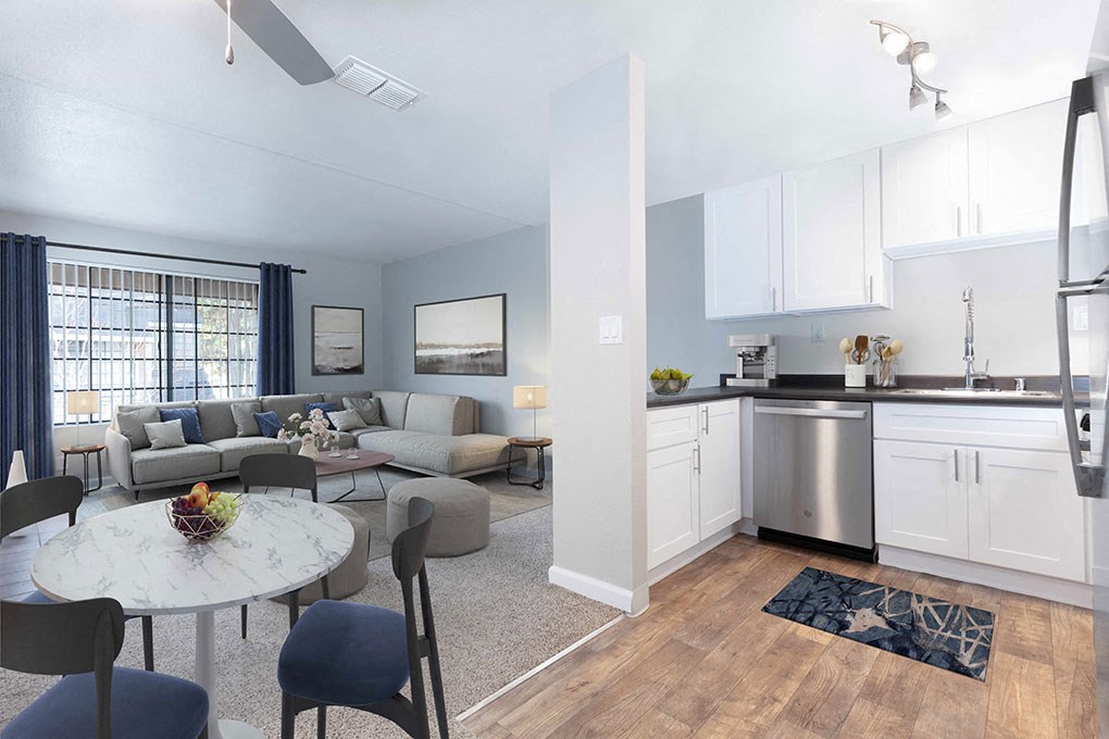 a living room with a couch a table and a chair and a kitchen with a sink and