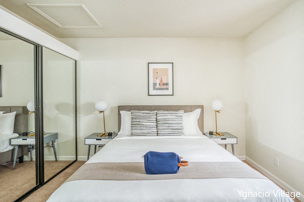 a bedroom with white walls and a large bed with a blue bag on top of it