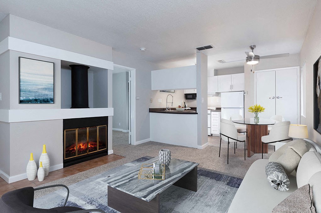 a living room with a fireplace and a kitchen in the background