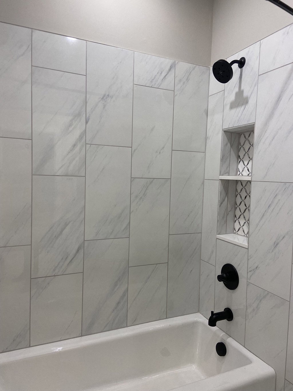 a view of the shower in a white tiled bathroom