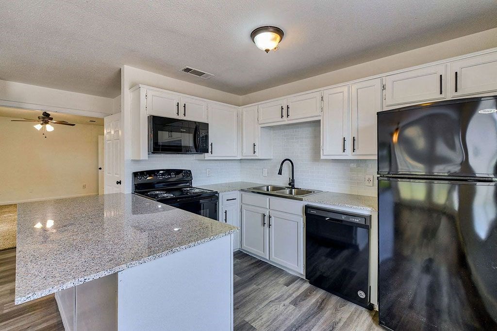 a kitchen with white cabinets and black appliances