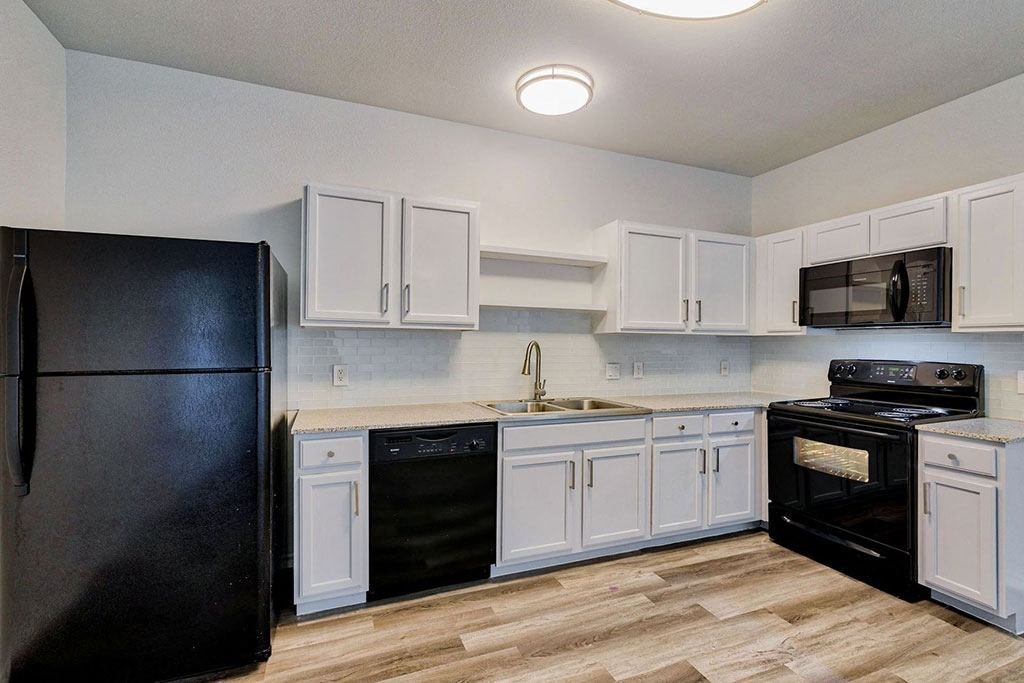 a kitchen with white cabinets and black appliances