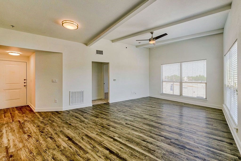 an empty living room with a large window and a ceiling fan