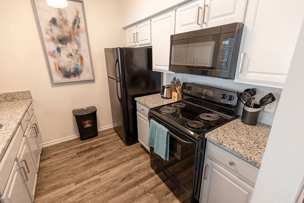 a kitchen with white cabinets and black appliances