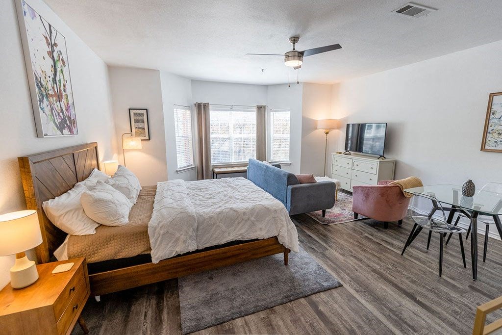 a bedroom with a bed and a couch in front of a tv