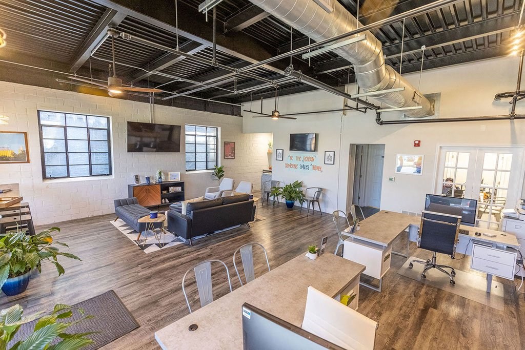 a room with couches and tables with computers on top of them