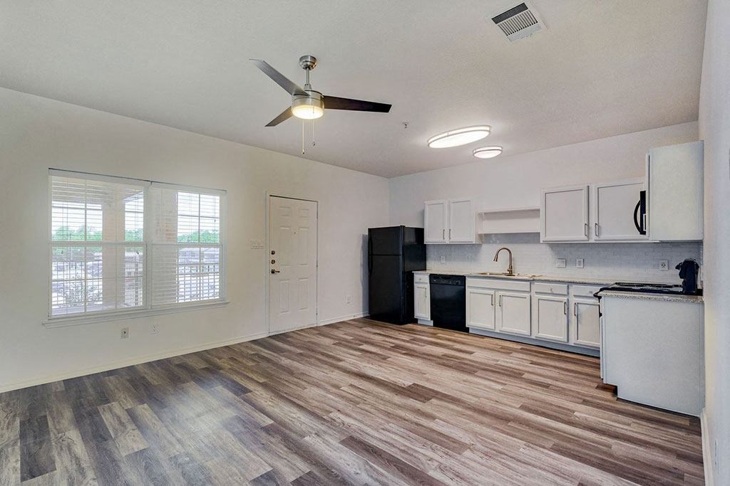 an empty kitchen and living room with a ceiling fan