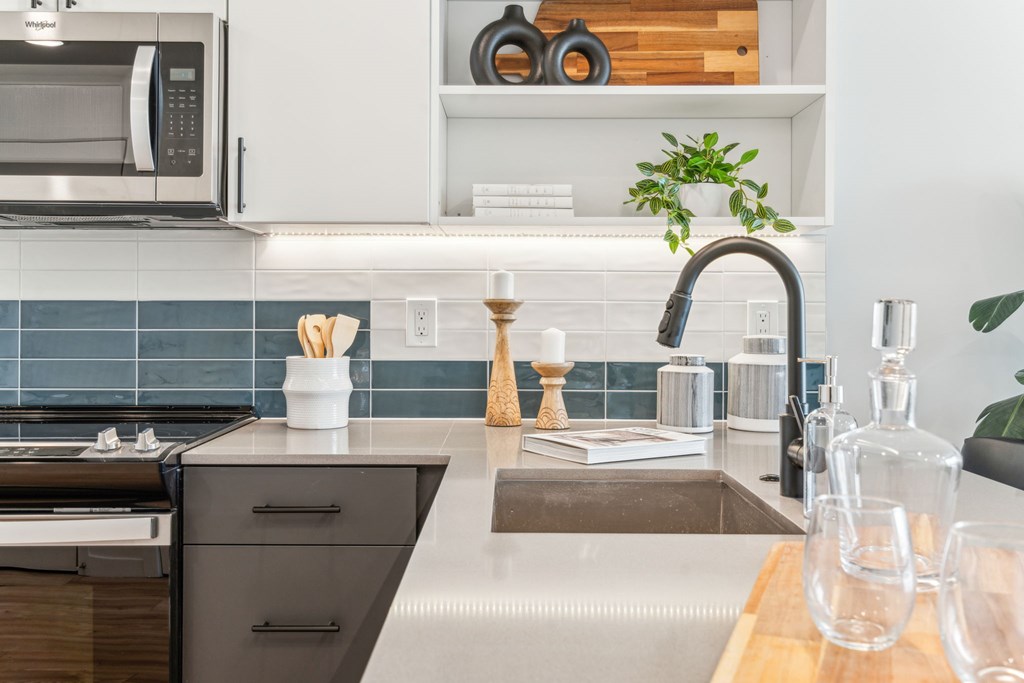 A modern kitchen with a stainless steel microwave and a wooden cutting board.