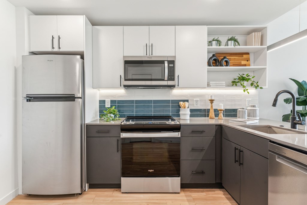 A modern kitchen with a refrigerator, microwave, oven, and sink.