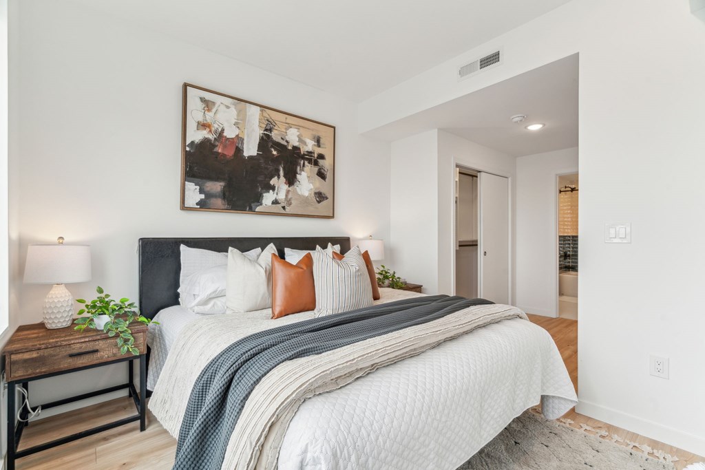 A bedroom with a large bed and a painting on the wall.