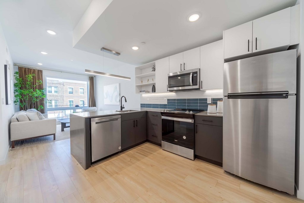 A modern kitchen with stainless steel appliances and wooden flooring.