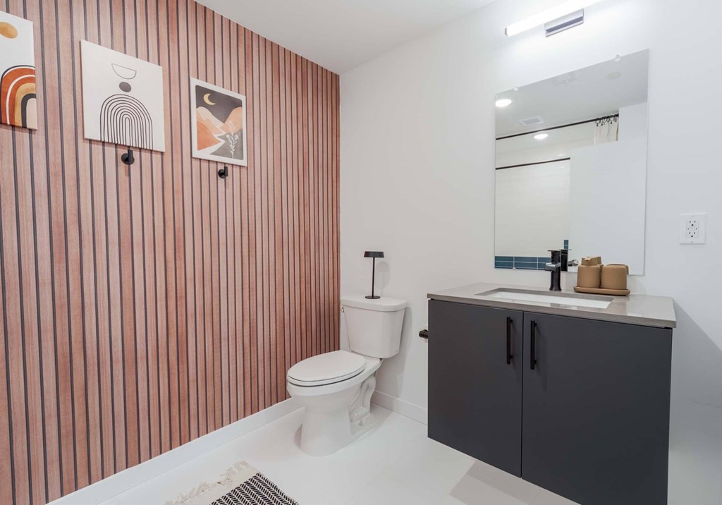 A bathroom with a toilet, sink, and striped wallpaper.