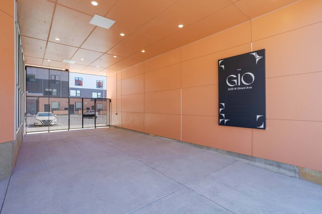 A sign for GIO is on the wall in a parking garage.