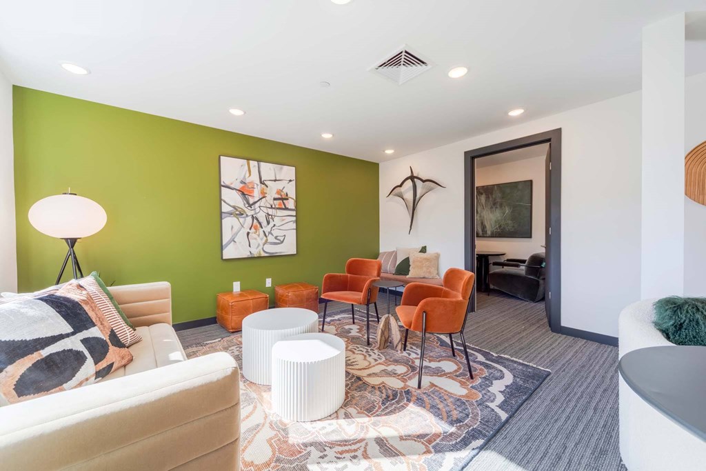 A living room with a white couch, orange chairs, and a rug.
