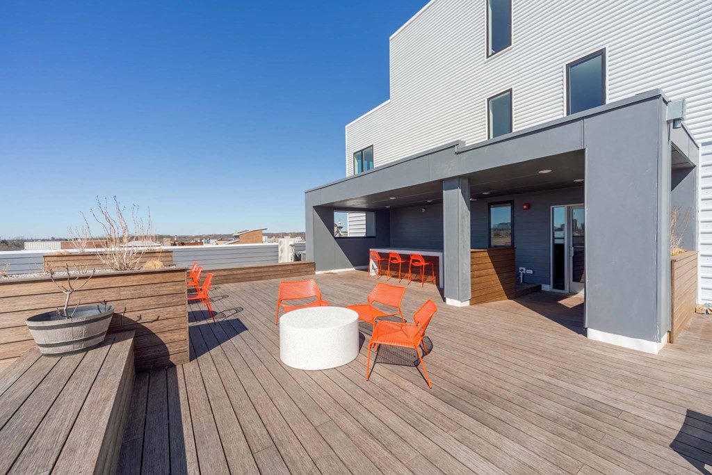 A modern deck with orange chairs and a white table.