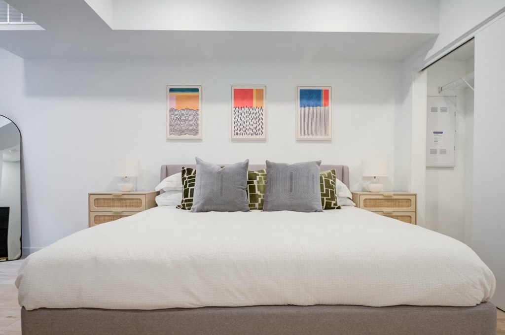 a bedroom with a large bed and three paintings on the wall