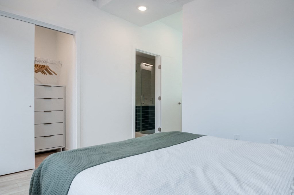 a white bedroom with a large bed and a closet