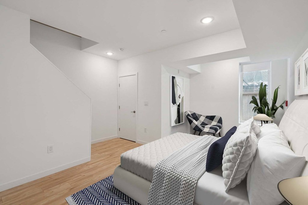 A bedroom with a bed, pillows, and a plant.