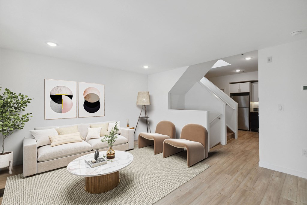 Cozy living area with a beige sofa, chic armchairs, a round marble coffee table, and modern wall art creating a welcoming ambiance.