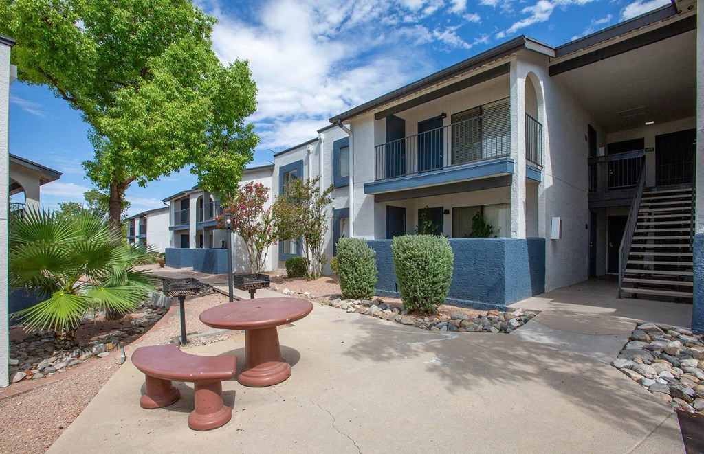 a courtyard with a picnic table and benches in front of an apartment building