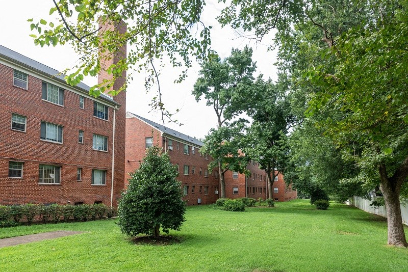 a brick building with a green lawn and trees