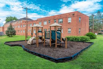 a playground in a yard in front of a brick building