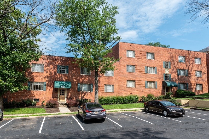 a large brick apartment building with cars parked in a parking lot