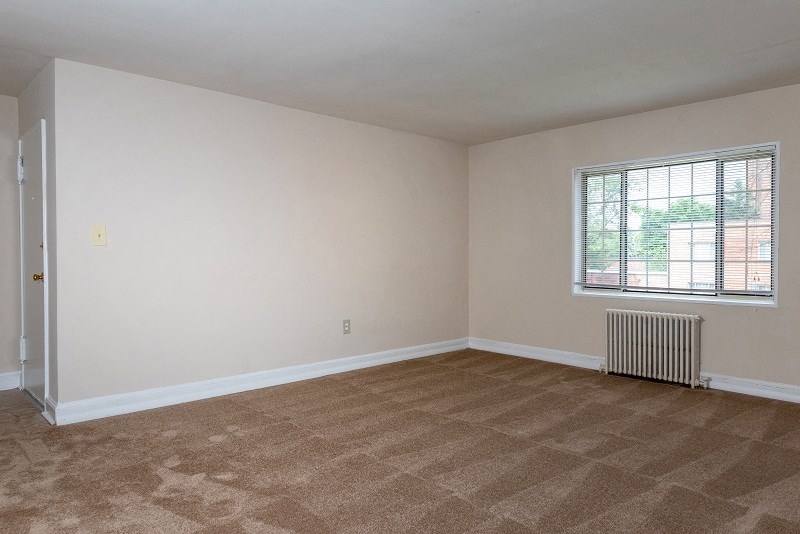 an empty living room with a radiator and a window