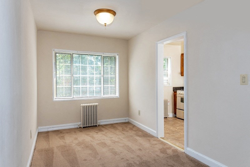 an empty living room with a window and a radiator
