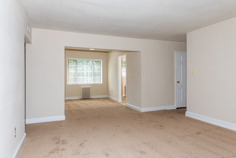 the spacious living room and dining room of an empty house