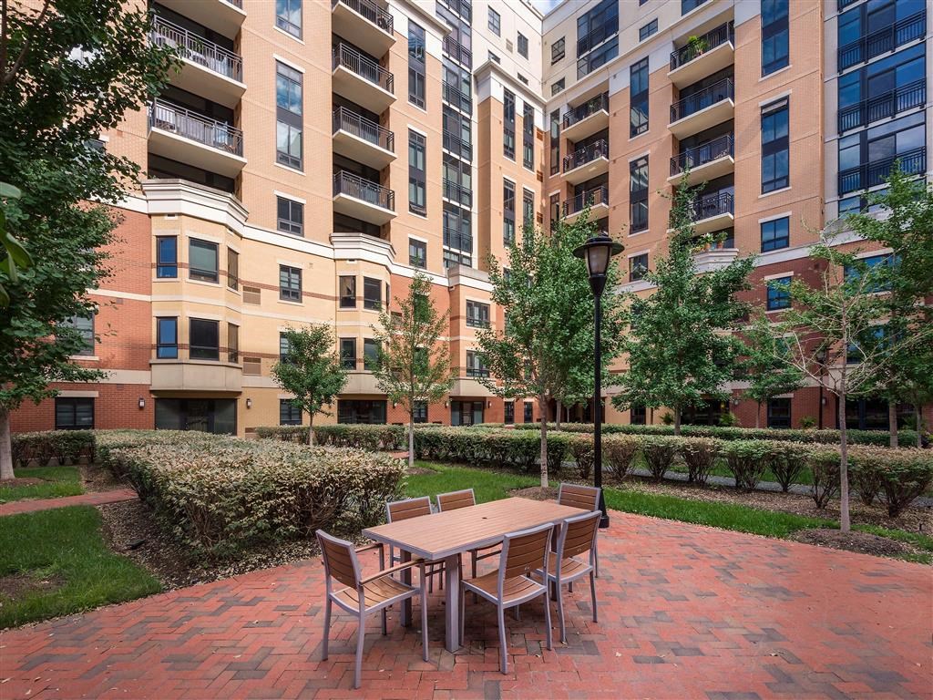 a patio with a table and chairs in front of an apartment building