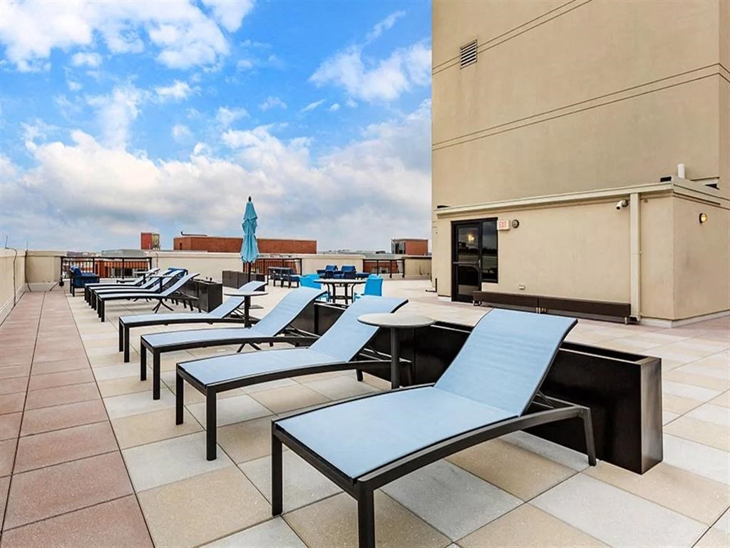 a row of lounge chairs and tables on a rooftop patio