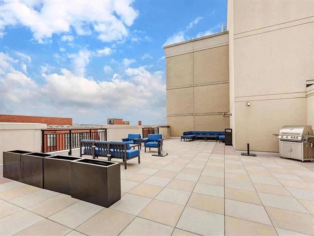 a rooftop patio with a grill and tables and benches
