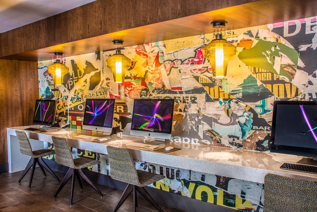 a row of desks with computers in a room with a wall covered in graffiti