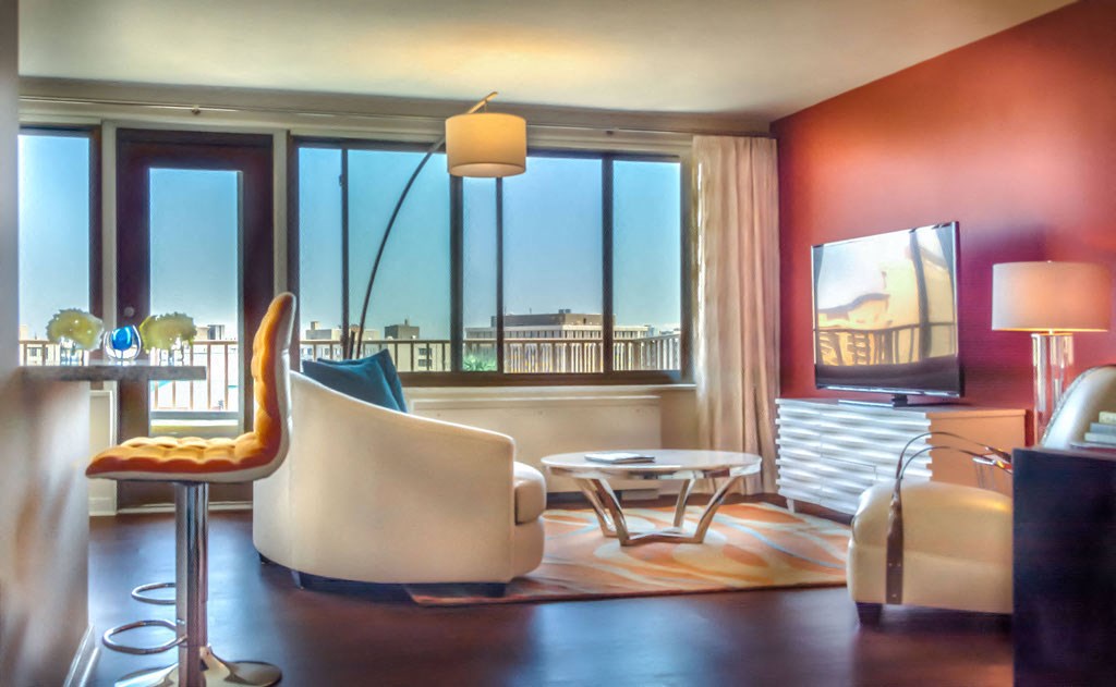 the living room of a hotel room with a view of the city