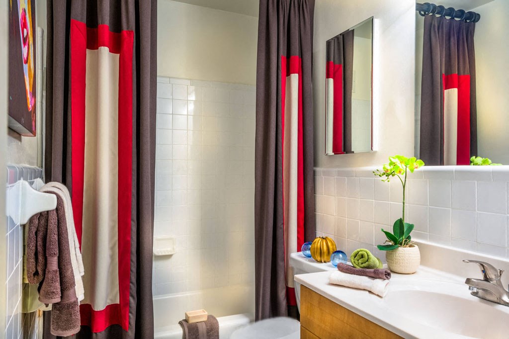 a bathroom with red and white shower curtains and a sink and a toilet