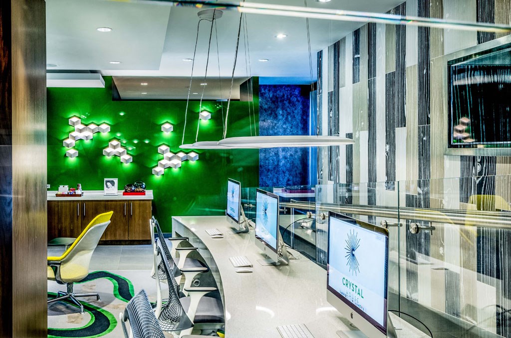 an office with green walls and a desk with computer monitors