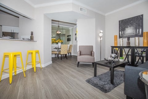 a living room with yellow bar stools and a dining room with a table